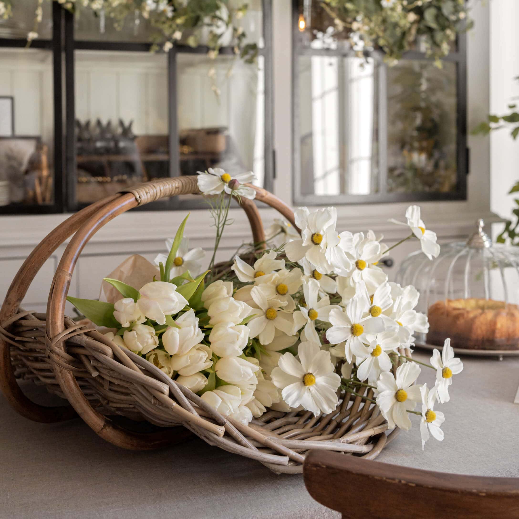 Wikinger Korb mit weißen Tulpen und dekorativen Blumen auf Tisch in hellem Raum
