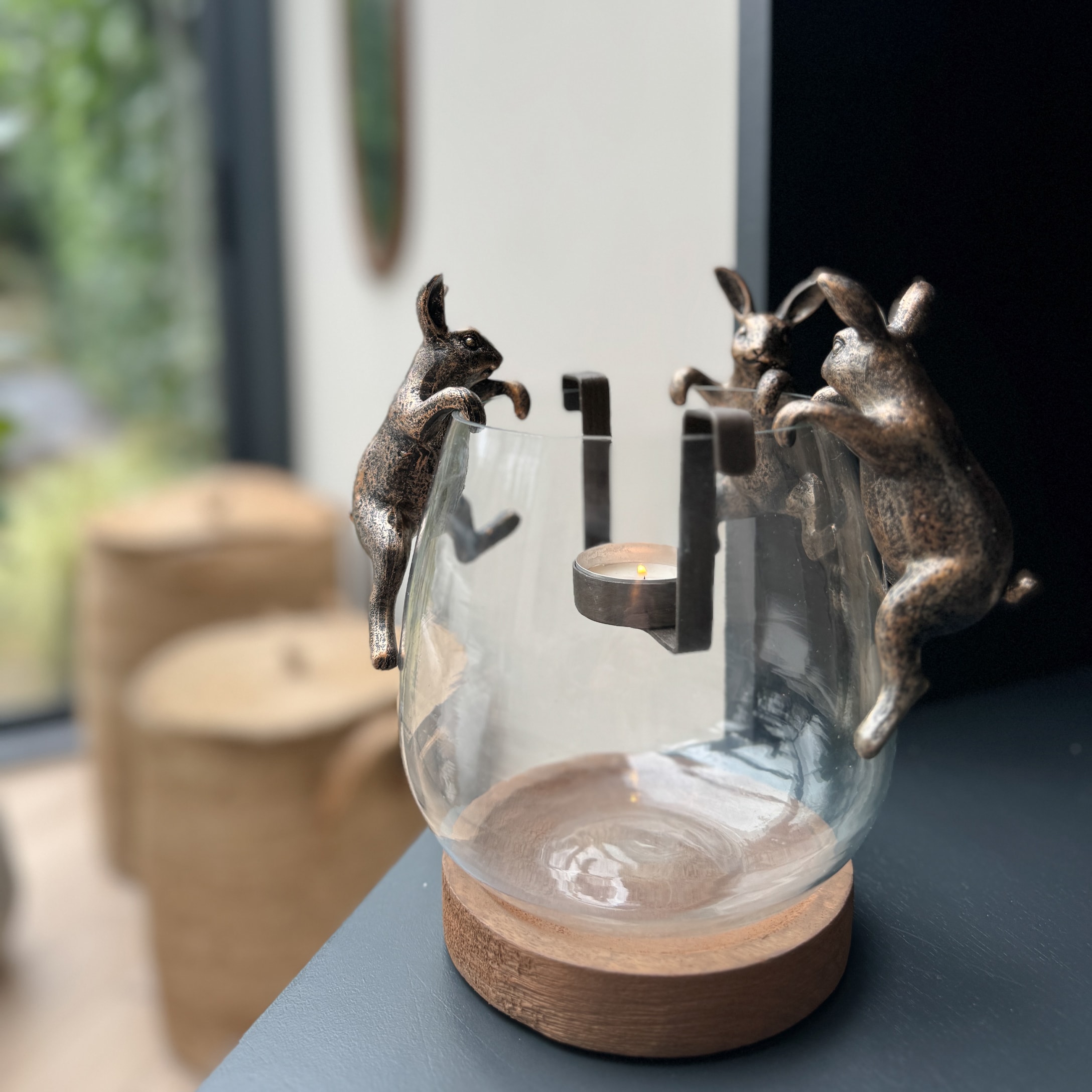 Glas-Teelichthalter mit Holzsockel und messingfarbenen Metallhasen als Wohnaccessoire