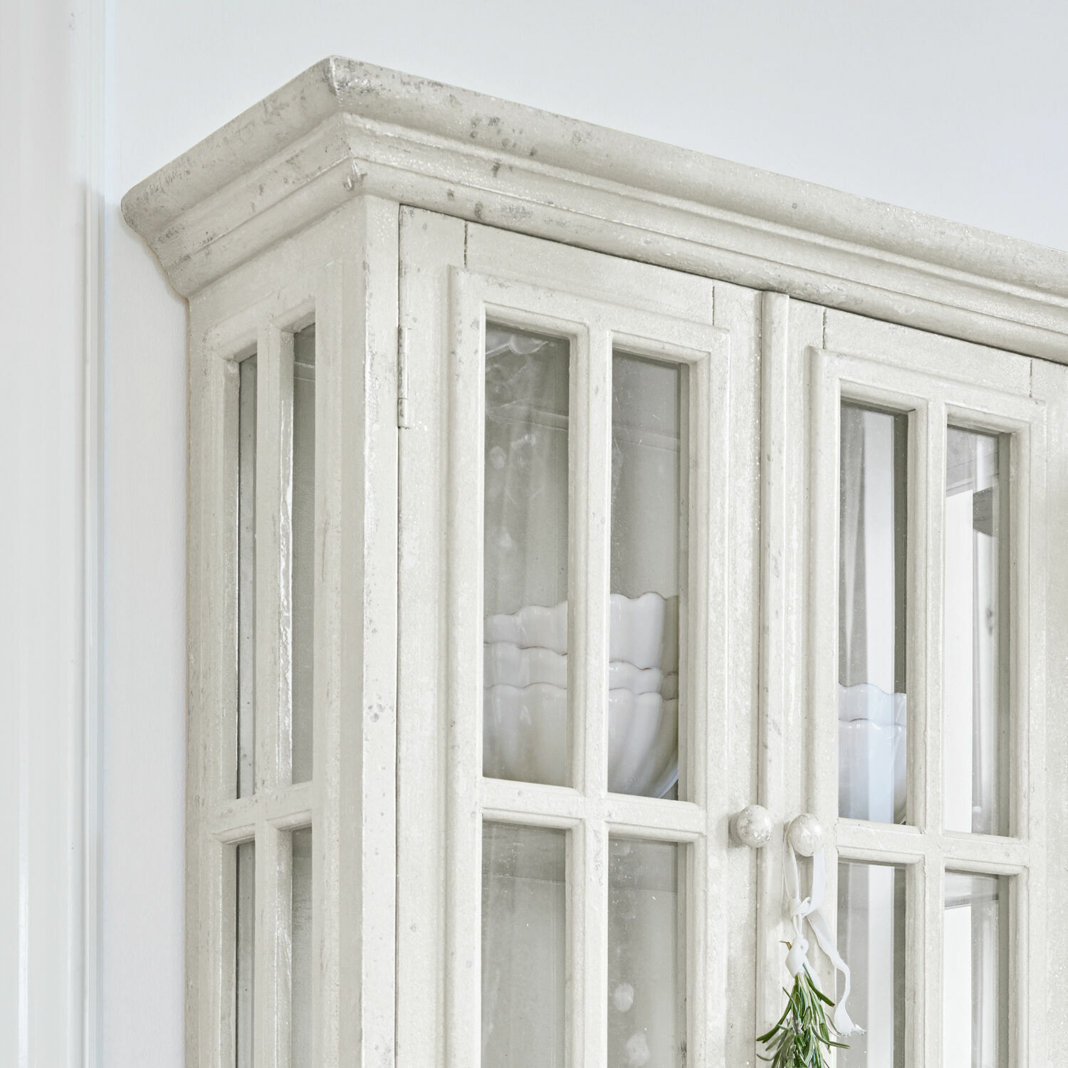 Weiße Holzvitrine mit Glastüren und Keramikschalen im Inneren