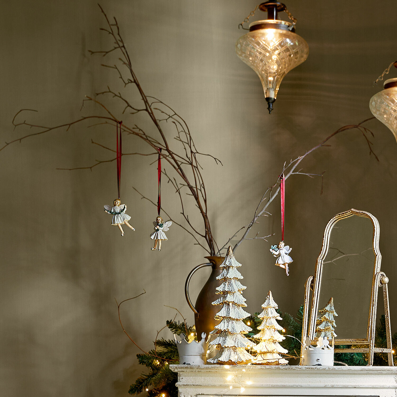 Weihnachtsdekoration mit weißen Tannenbäumen und Engeln an Zweigen in Vase auf Kommode mit Spiegel