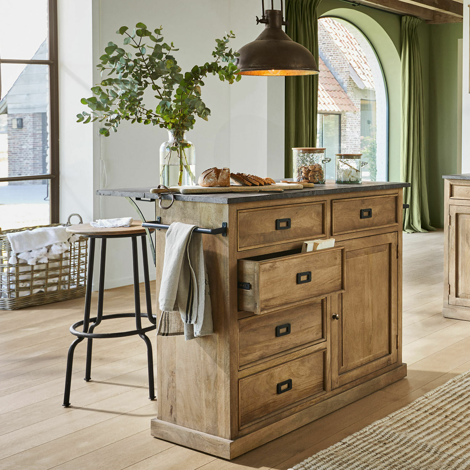 Kücheninsel aus Mangoholz mit grauer Steinplatte, offenen Schubladen und Brotdekoration im Landhausstil
