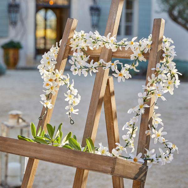 Holzstaffelei mit weißer Blumen- und grüner Blattdekoration im Außenbereich, Gartendekor