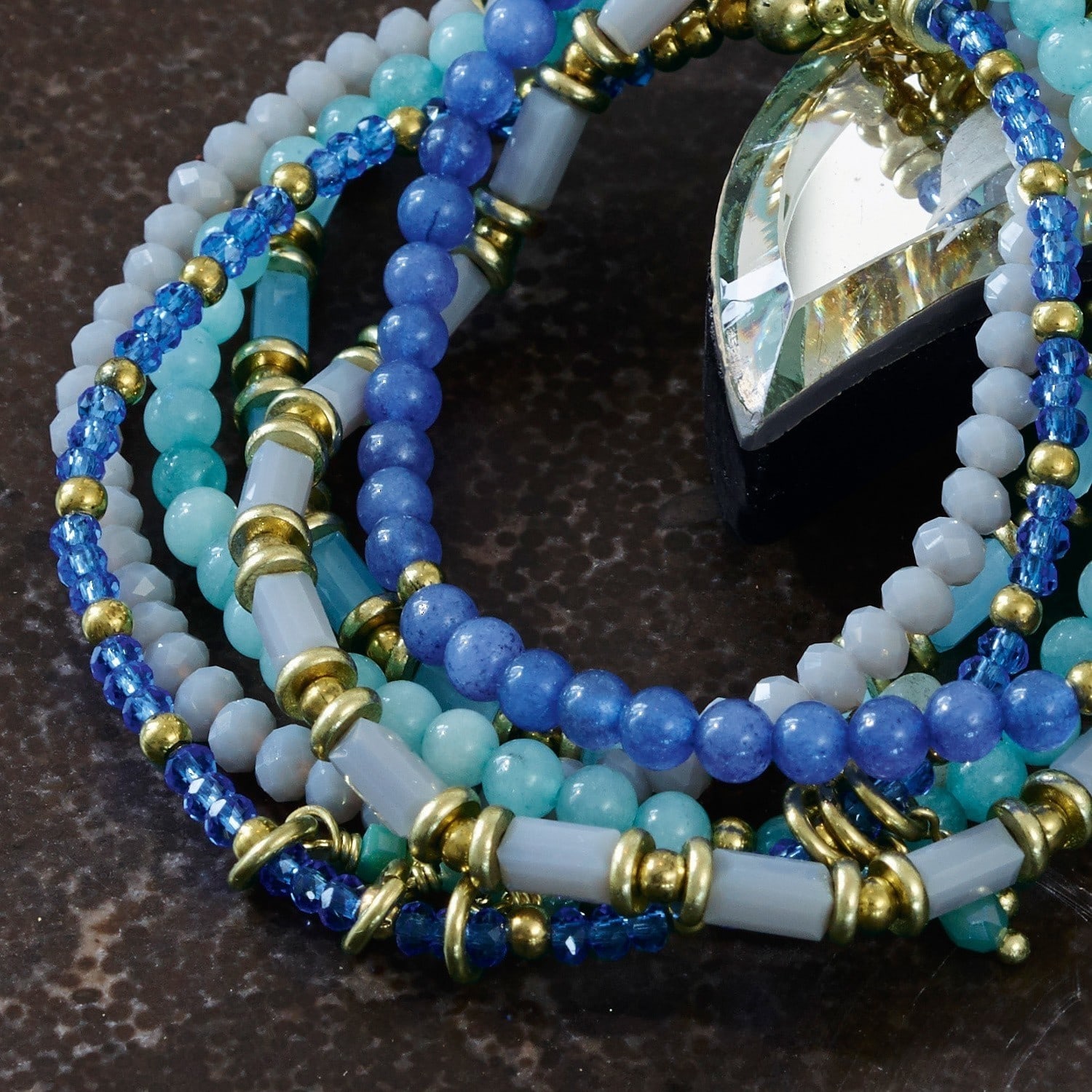 Bunte Armband aus blauen und goldenen Perlen auf dunklem Hintergrund, modisches Schmuckstück