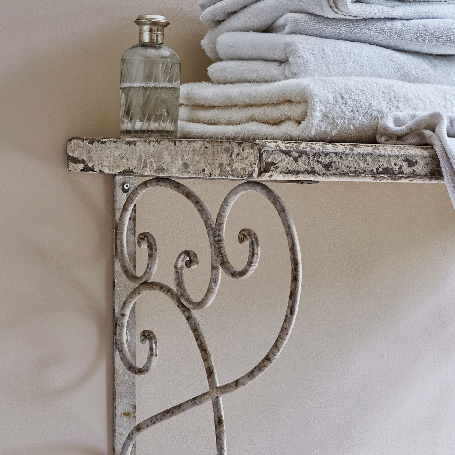 Metallregal mit dekorativem Muster und weißen Handtüchern an beiger Wand im Badezimmer