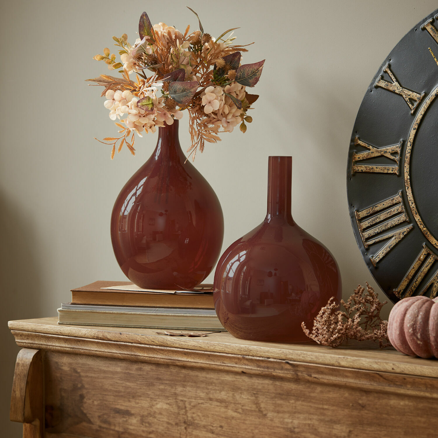 Vase 2er Set Erlunda Zwei braune Glasvasen auf Holzkommode mit dekorativen Trockenblumen und Büchern