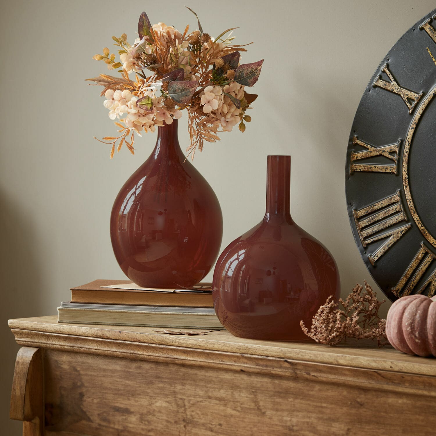Vase 2er Set Erlunda Zwei braune Glasvasen auf Holzkommode mit dekorativen Trockenblumen und Büchern