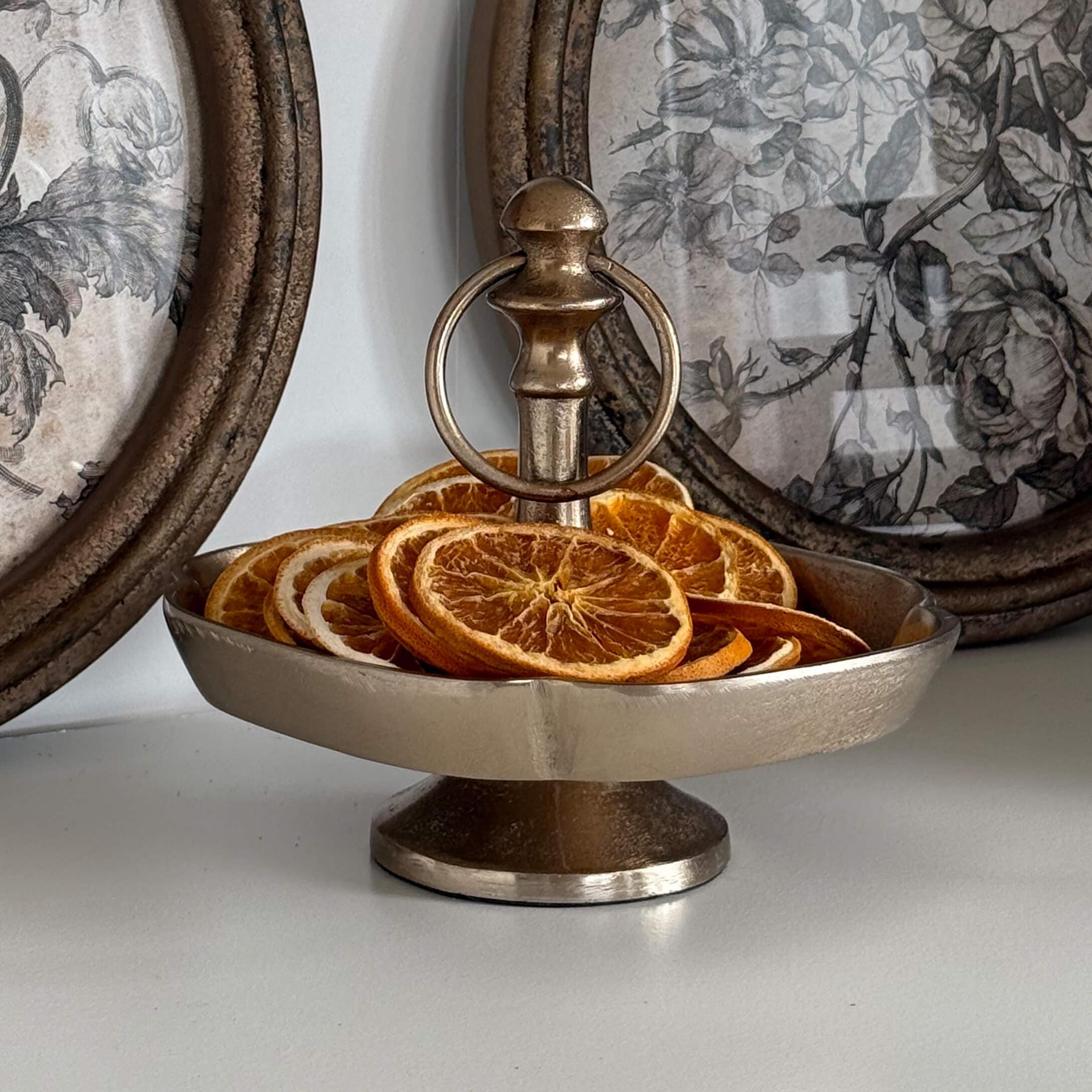 Silberne Metall-Etagere mit Griff, gefüllt mit getrockneten Orangenscheiben als herbstliche Dekoration
