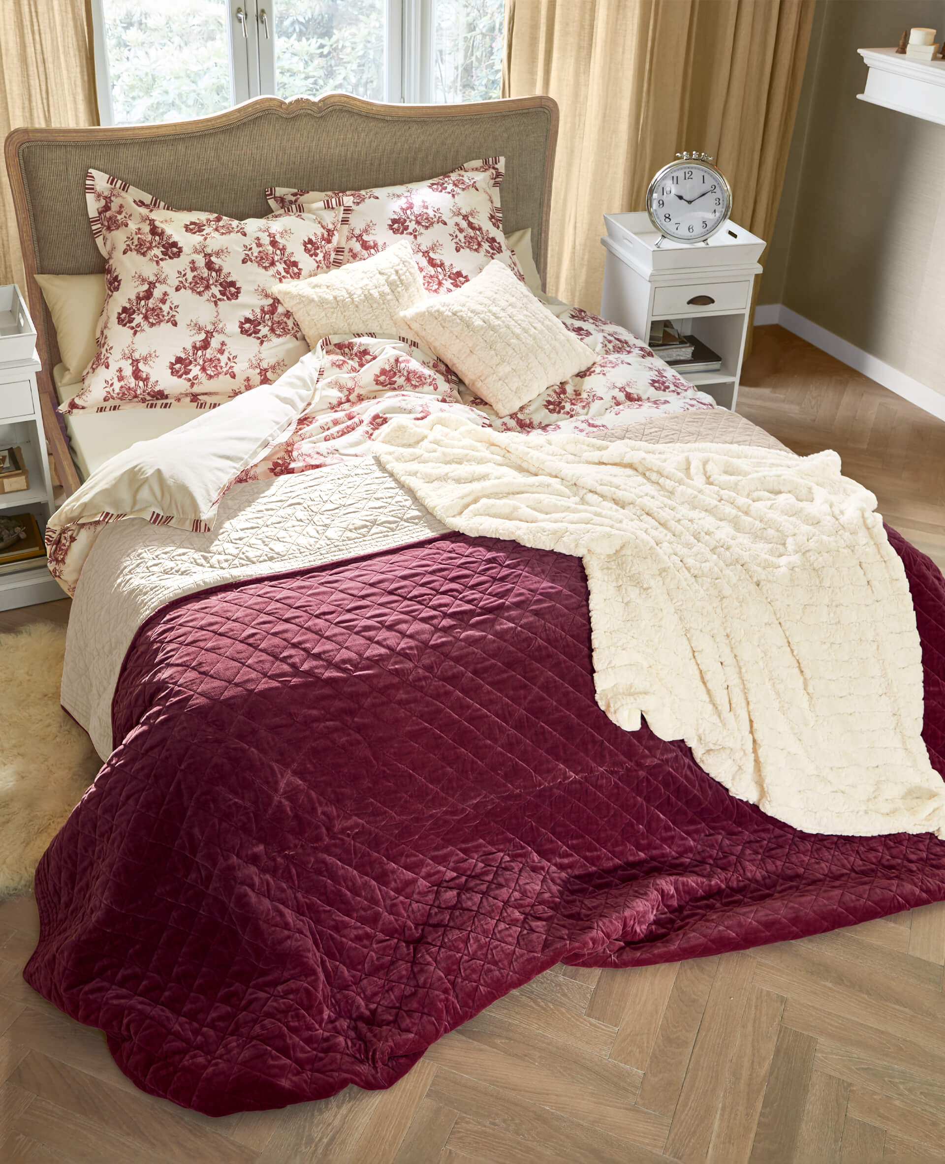 Gemütliche Bettwäsche mit rotem Blumenmuster und bordeauxfarbenem Steppbett im Schlafzimmer