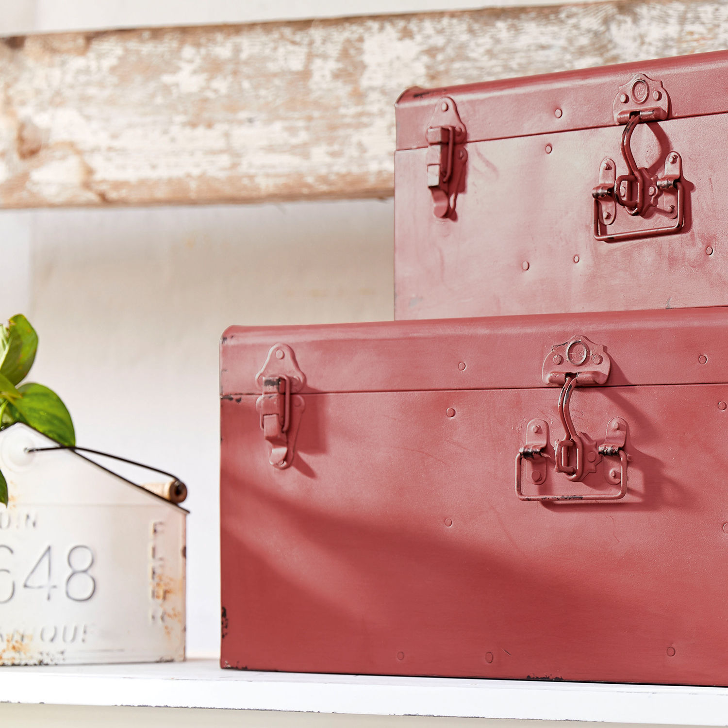 Zwei rote Metallboxen mit Verschlüssen auf weißem Regal, vintage Aufbewahrungsdekoration