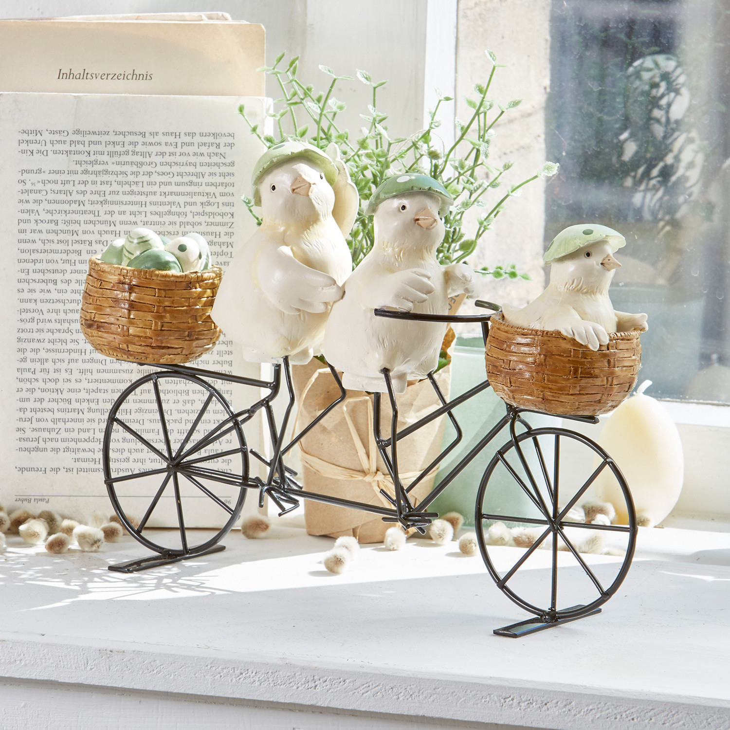 Dekoration mit drei weißen Vögeln mit grünen Hüten auf Metallfahrrad mit Korb aus Weide