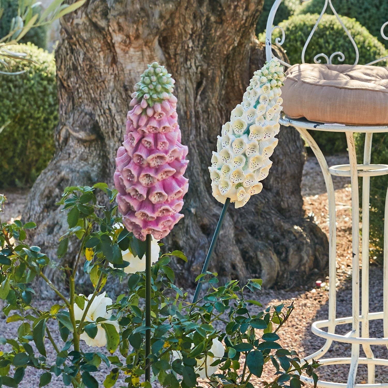 Dekorative Gartenblumen in Rosa und Creme auf Metallständern in natürlicher Umgebung im Garten