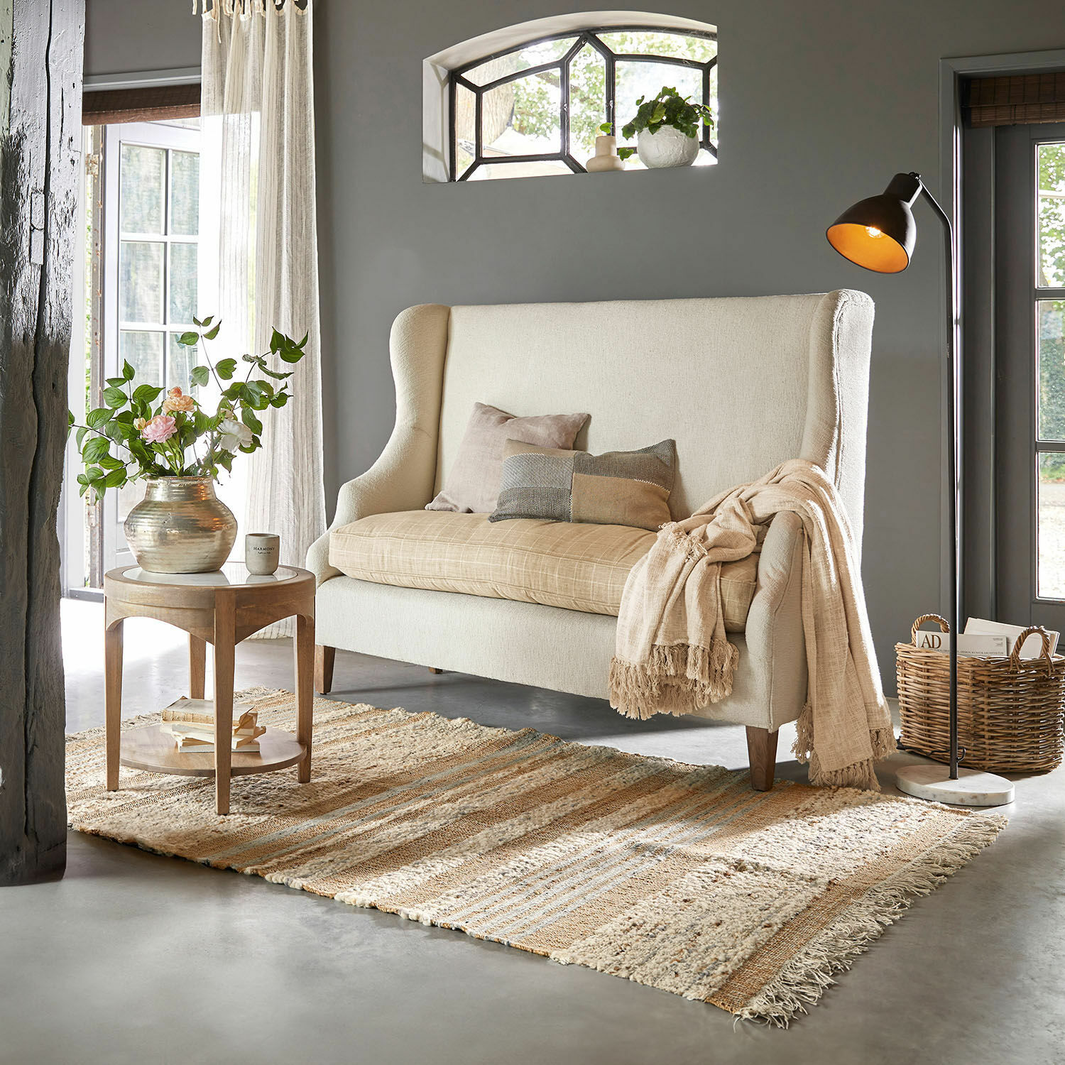 Teppich Cassidy Beige Sofa mit hohem Rücken und Kissen in gemütlichem Wohnzimmer mit Teppich und Stehlampe