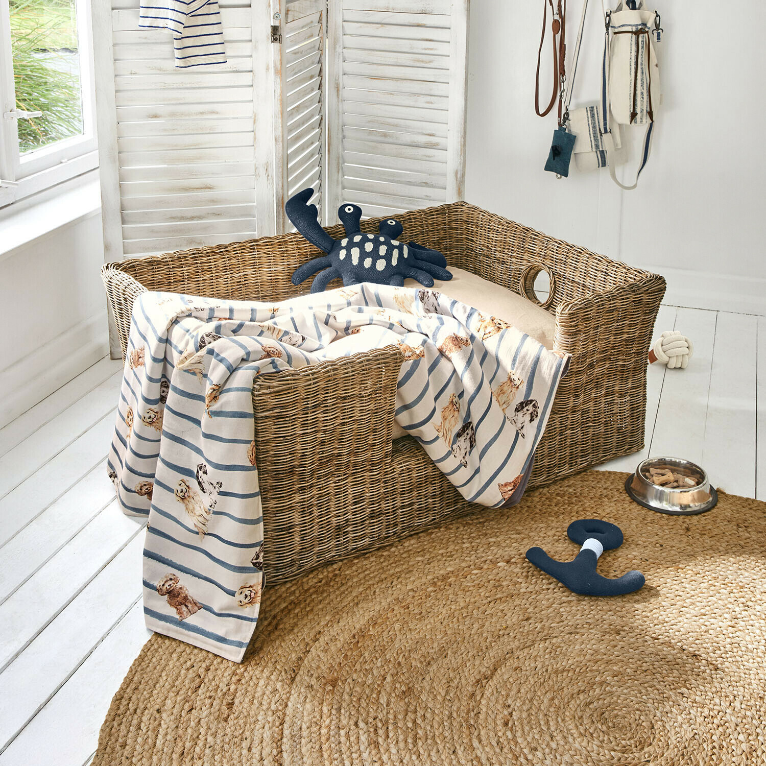 Haustierkorb Knuddo Wicker-Hundebett mit beigem Kissen, gestreifter Decke mit Hunde-Motiv, Spielzeug und Futternapf mit Leckerlis