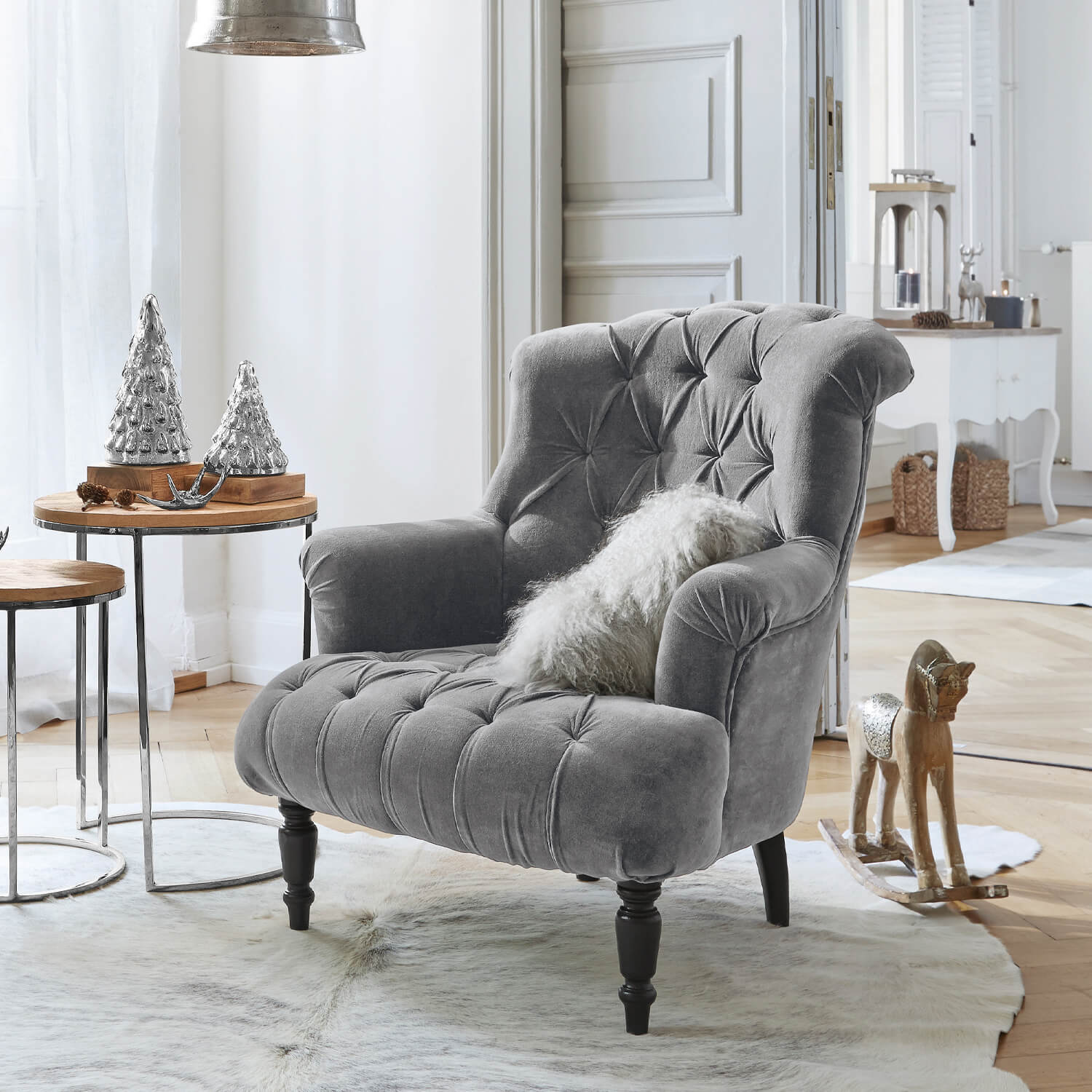Grauer Samtfotel mit gesteppter Rückenlehne und schwarzen Beinen in hellem Wohnzimmer mit Weihnachtsdeko