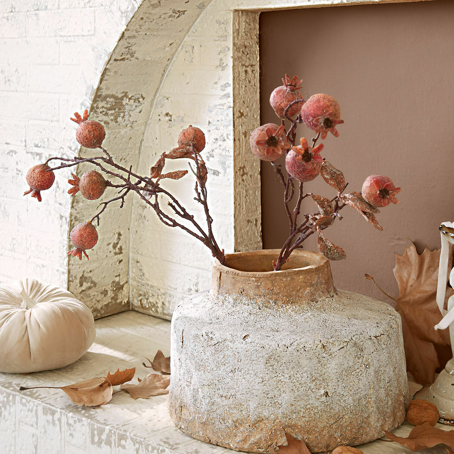 Rustikaler beiger Keramikvase mit getrockneten Granatäpfeln als Dekoration auf Regal