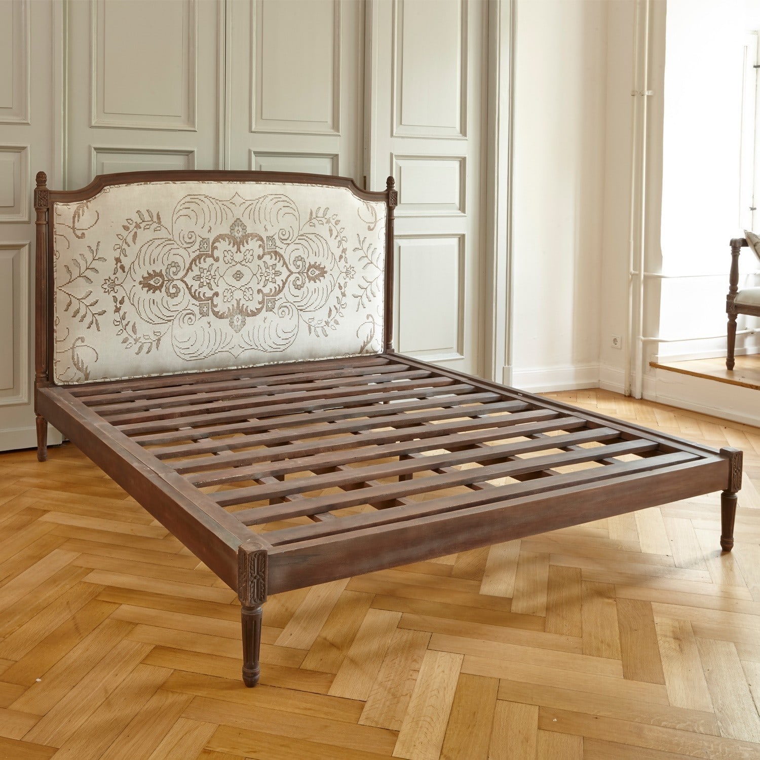 Dunkles Holzbett mit cremefarbenem, gemustertem Polsterkopfteil im Vintage-Stil
