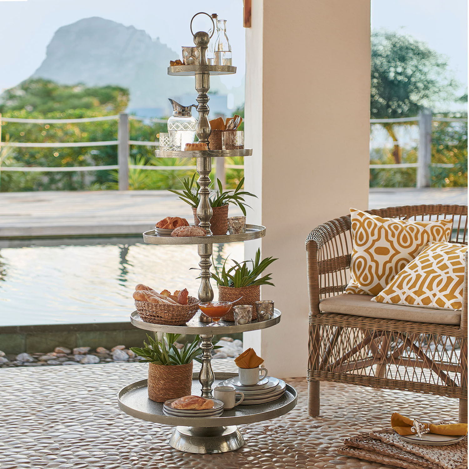 Fünfstöckige Metall-Etagere mit Dekorationen und Snacks auf Terrasse am Pool