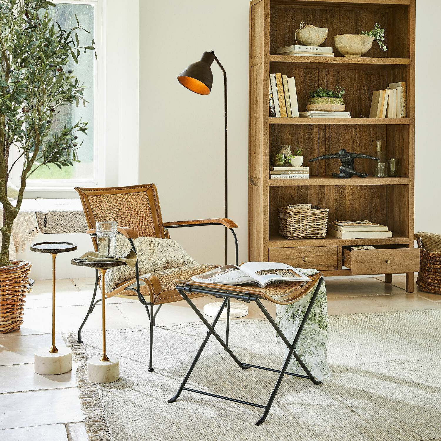Bequemer Rattan-Metall-Sessel in Naturfarbe mit Hocker und Stehlampe im hellen Wohnzimmer