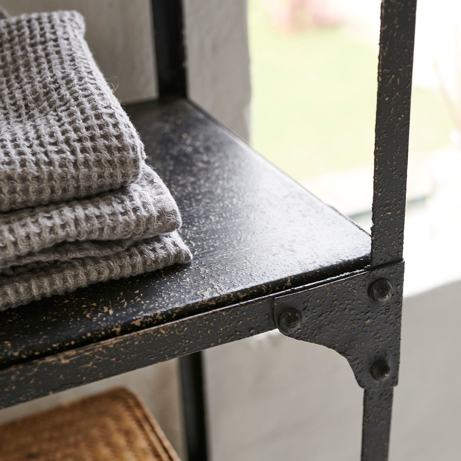 Schwarzes Metallregal mit strukturierter Oberfläche und grauen gefalteten Handtüchern im Loft-Stil