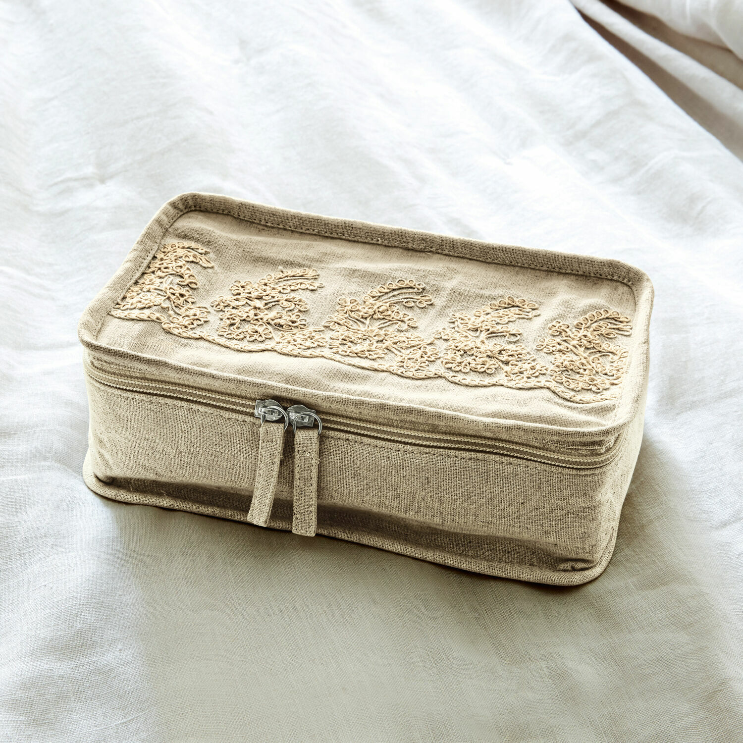 Beige Leinen-Kosmetiktasche mit besticktem Muster und Reißverschluss auf hellem Hintergrund