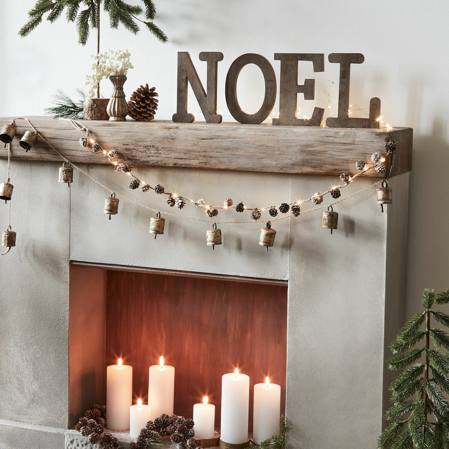 Weihnachtliche Kamin-Dekoration mit Holzbuchstaben NOEL und Girlande aus Glocken und Zapfen