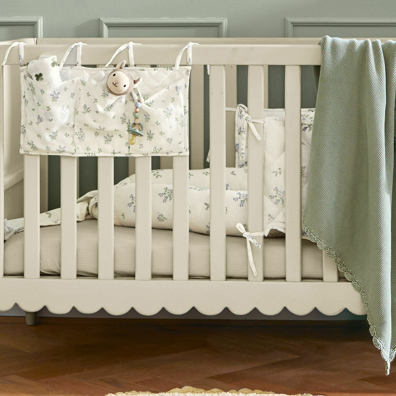 Beige Babybett mit Baumwollbettwäsche in Blumenmuster und grünem Kuscheldecke