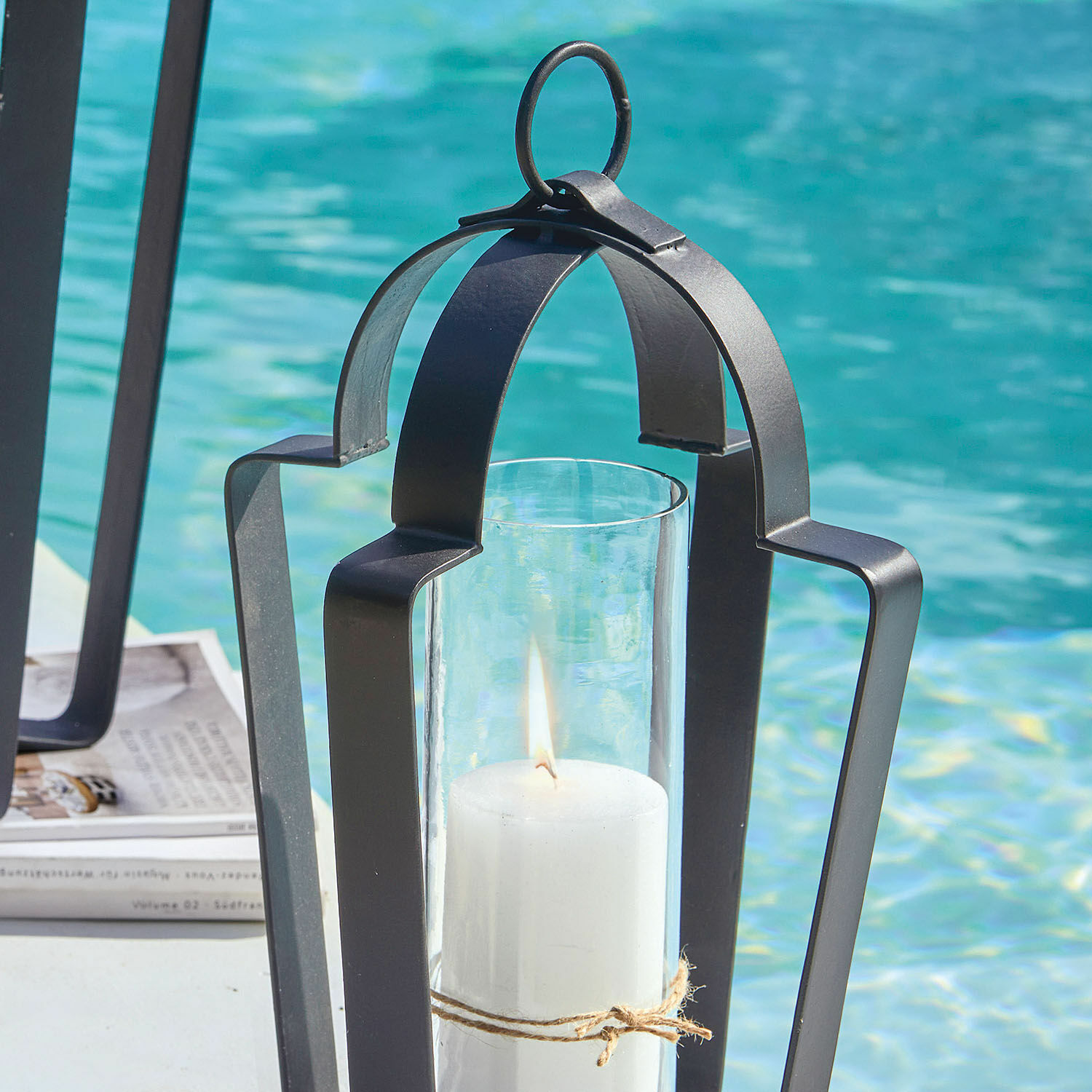 Schwarze Metalllaterne mit weißer Kerze am Pool, stilvolle Outdoor-Dekoration