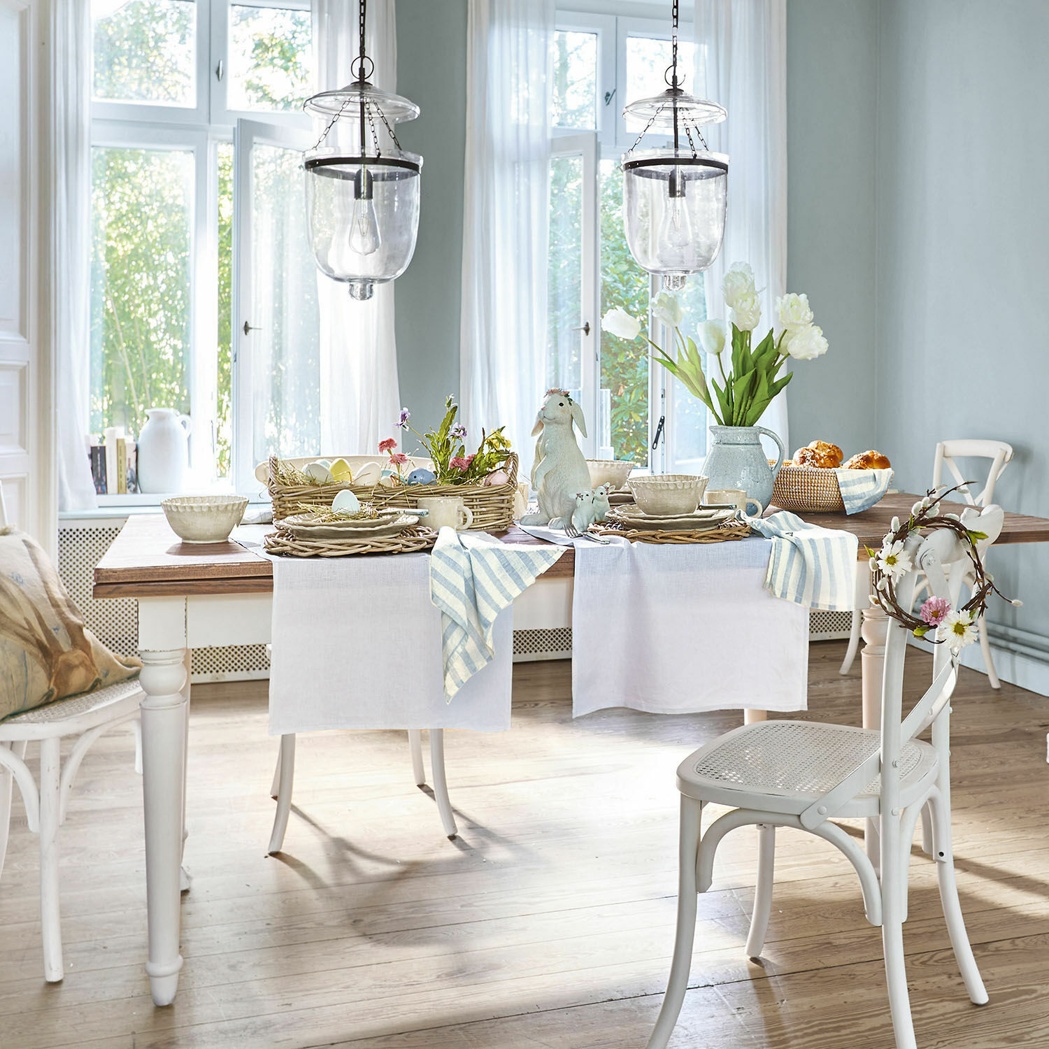 Esszimmer mit weißem Holztisch und Stühlen, dekoriert mit Frühlingsblumen und Dekorationen