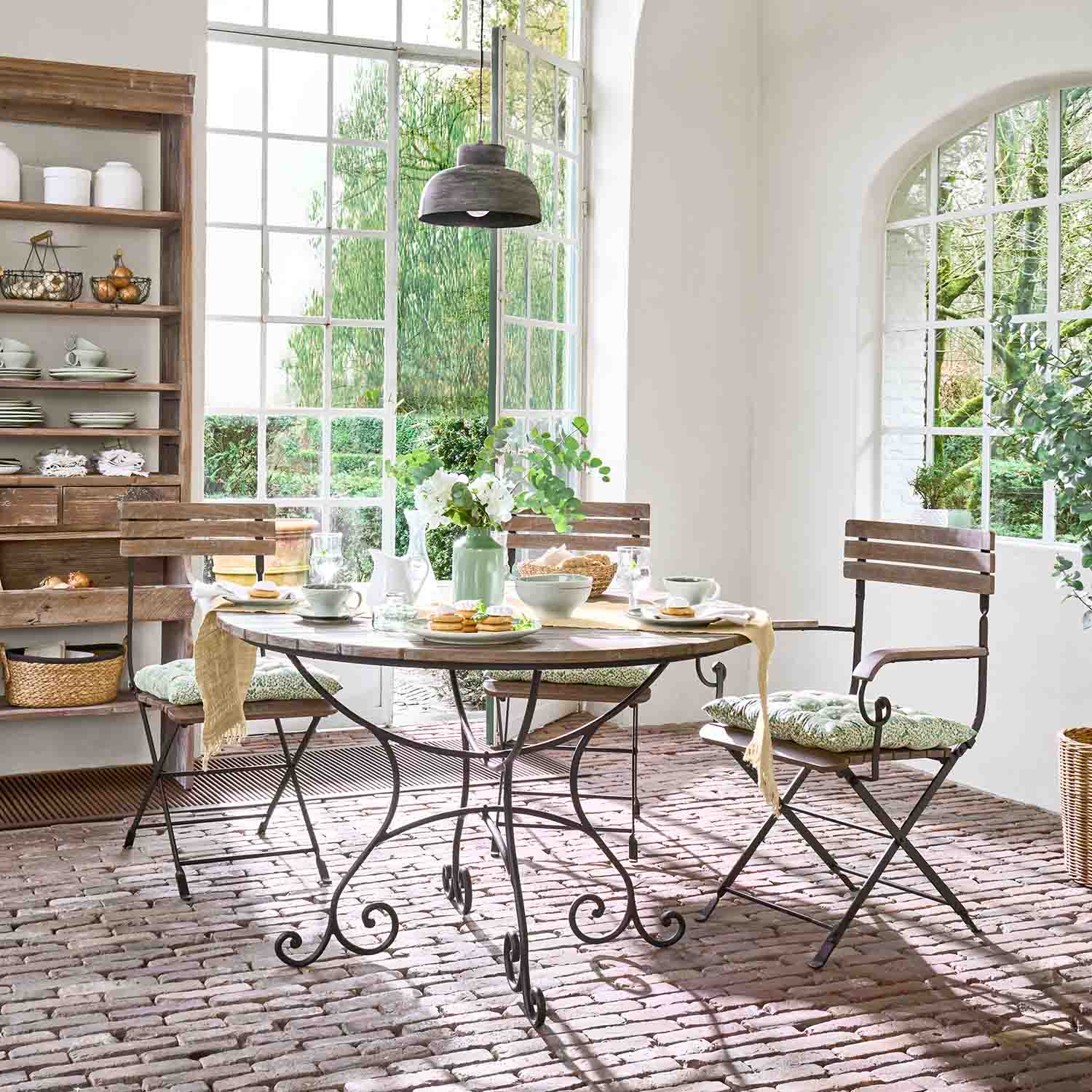 Runder Holztisch mit Metallgestell und Stühle mit Polstern in hellem, sonnigem Esszimmer