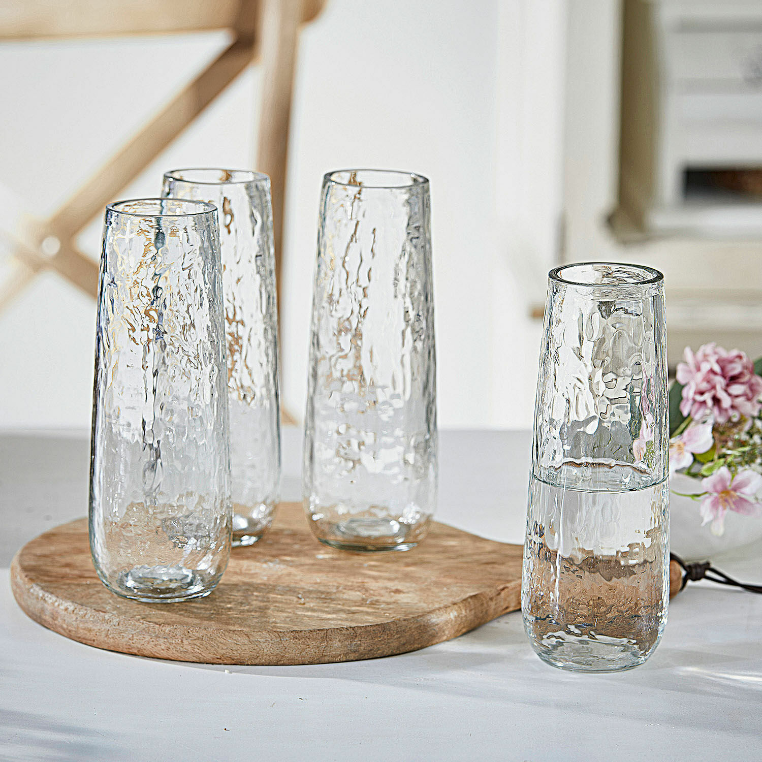 Set aus vier hohen Gläsern aus klarem, strukturiertem Glas auf einem Holzbrett