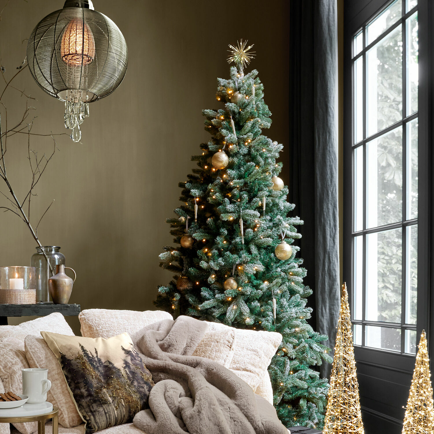 Gemütliches Wohnzimmer mit grünem Weihnachtsbaum, goldenen Kugeln und warmem Lichterglanz neben Fenster