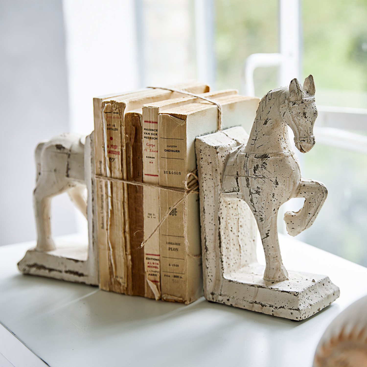 Buchstütze 2er Set Horses Weiße Keramik-Buchstützen in Pferdeform mit alten, gebundenen Büchern auf einem Tisch