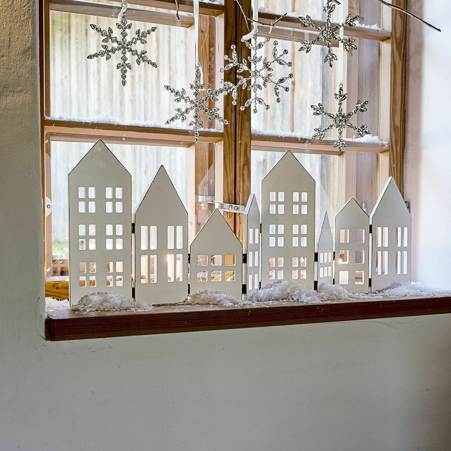 Deko-Shutter Cottages Weiße Holzhaus-Dekoration auf Fensterbank mit hängenden Schneeflocken für winterliche Stimmung