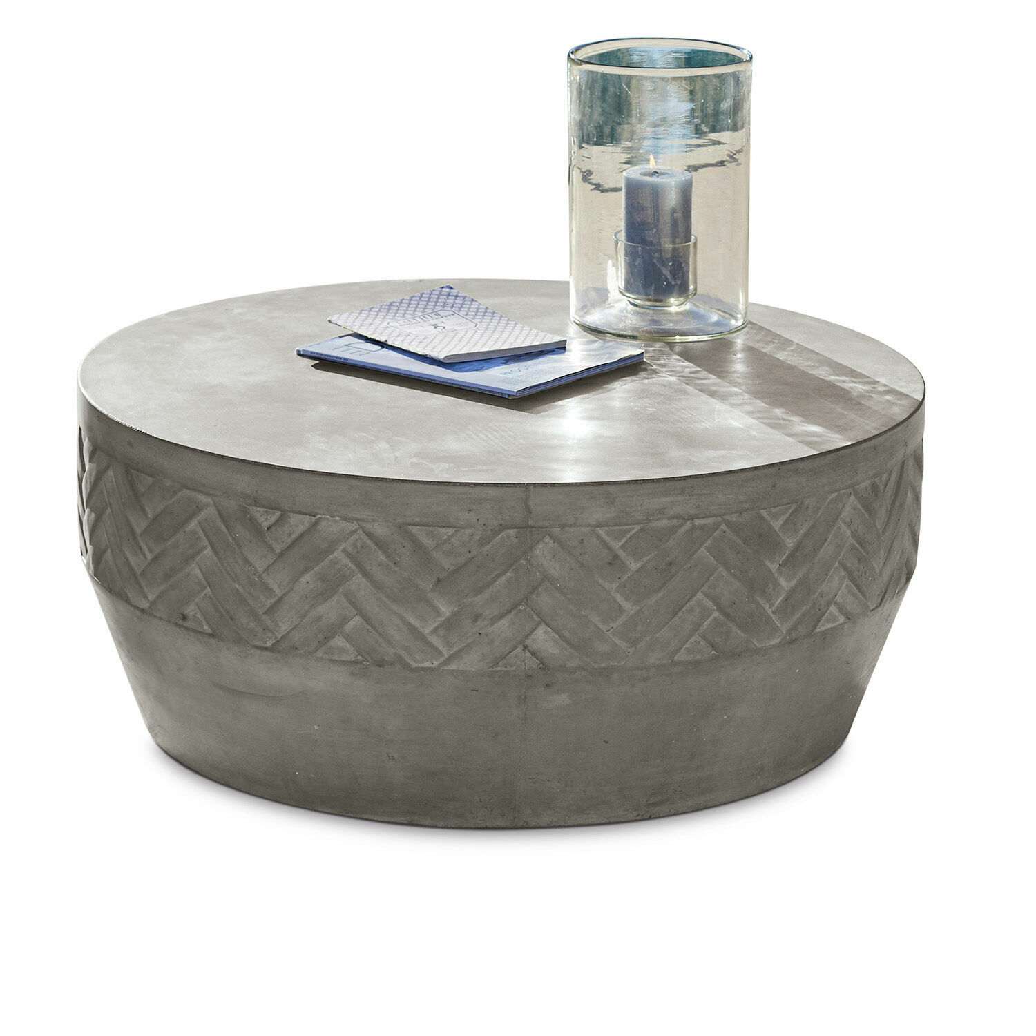 Runder Couchtisch aus grauem Beton mit geometrischem Muster und Kerze im Glaswindlicht