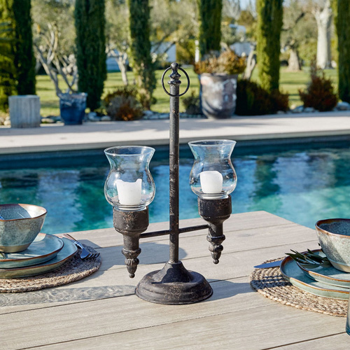 Metall-Kerzenhalter mit zwei Glashüllen für Kerzen, draußen am Pool auf Holztisch