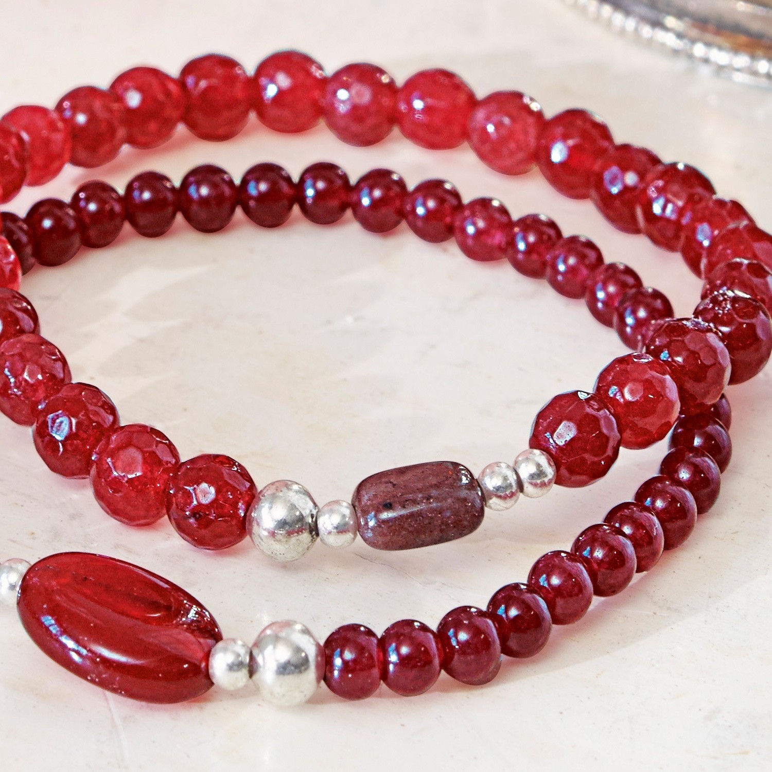 Armbänder aus roten Perlen mit silbernen Akzenten auf hellem Hintergrund, Modeschmuck