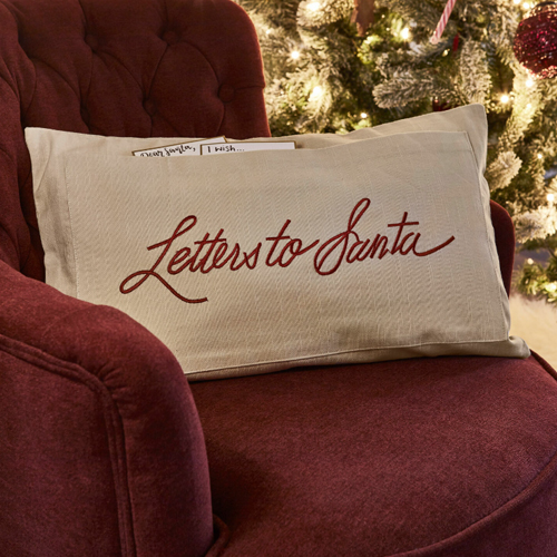Beige Kissenhülle mit Schriftzug Letters to Santa auf bordeauxrotem Sessel neben Weihnachtsbaum