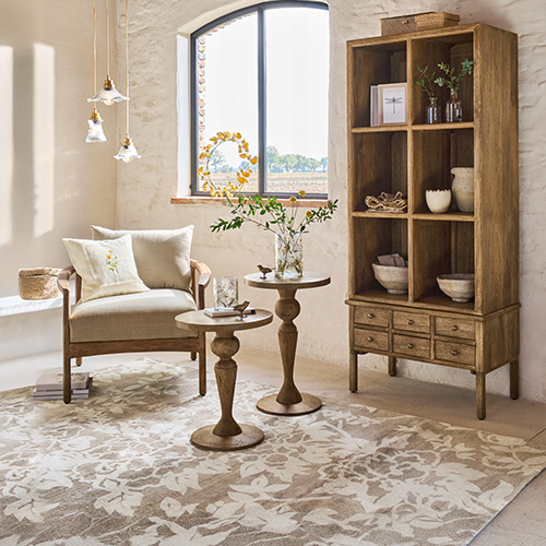 Holzschrank mit Regalen und Schubladen, Beistelltische und Sessel in hellem, natürlichem Raum mit Teppich