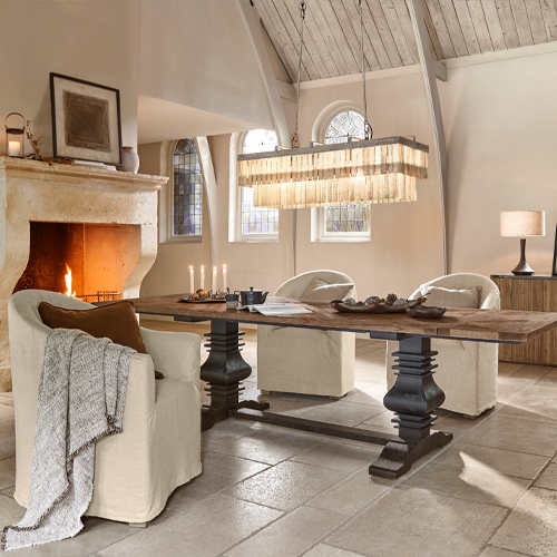Esszimmer mit rustikalem Holztisch und cremefarbenen Polstersesseln am Kamin, gemütlicher Stil