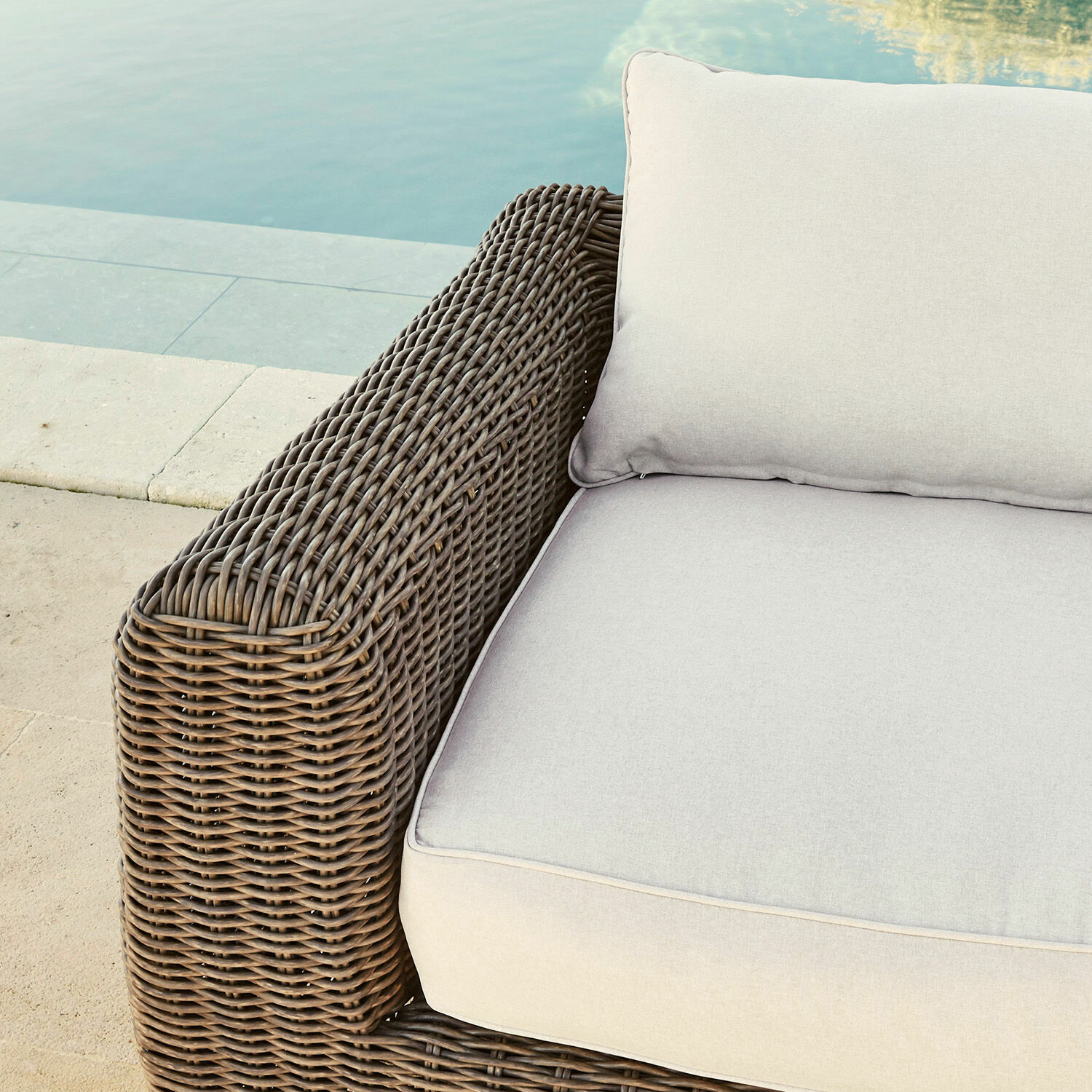 Braunes Rattanmöbel mit hellgrauen Kissen, ideal für Terrasse am Pool