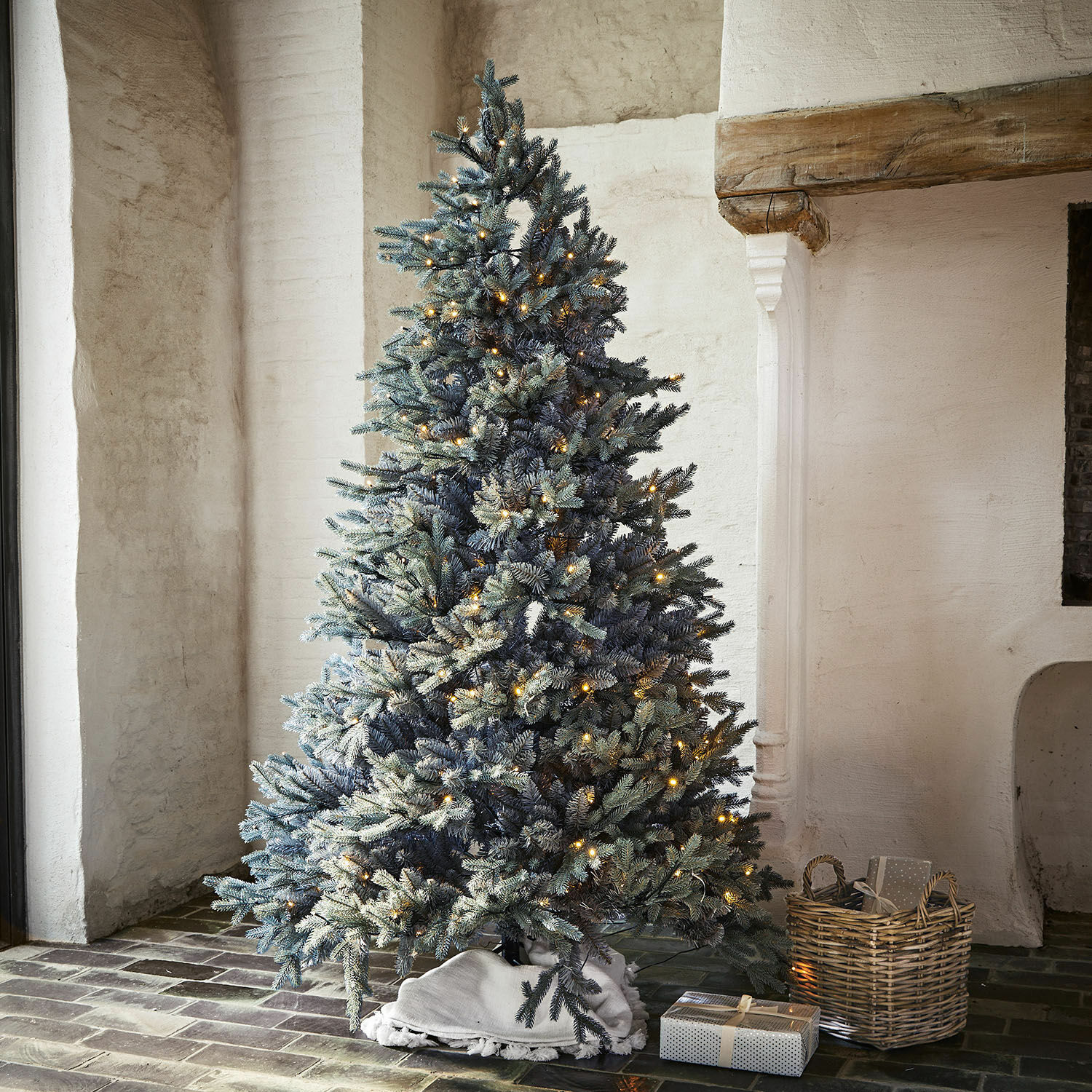 Weihnachtsbaum Patrick Künstlicher Weihnachtsbaum mit schneebedeckten Zweigen und warmen LED-Lichtern im rustikalen Raum