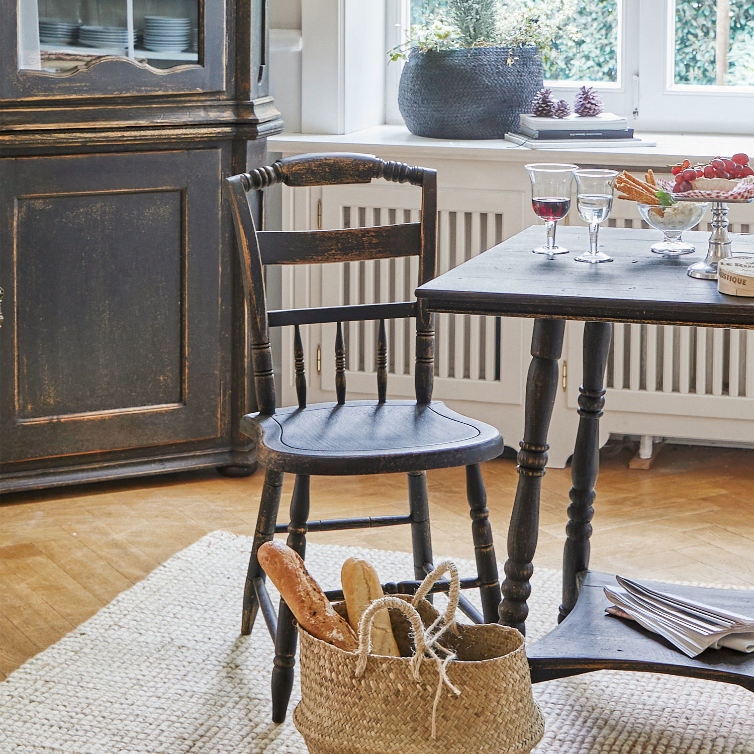 Schwarzer Holztisch und Stuhl im Vintage-Stil in hellem Wohnzimmer mit Brotkorb