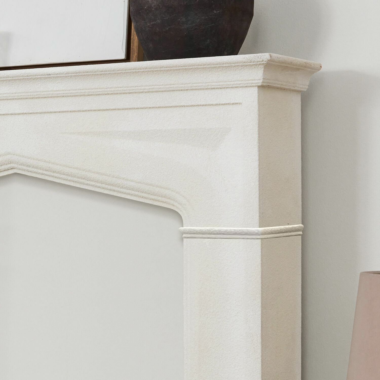 Weißer Steinkamin mit feiner Verzierung, elegantes Dekorelement für das Wohnzimmer