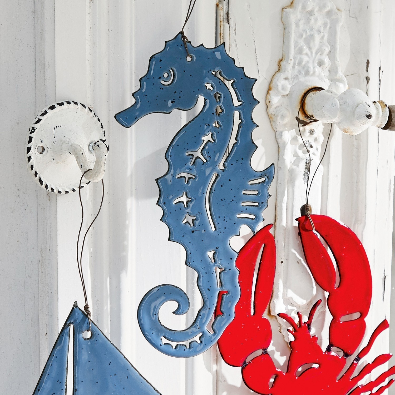 Blaue Metall-Wanddekoration in Form eines Seepferdchens an weißem Hintergrund, maritime Wohnaccessoire