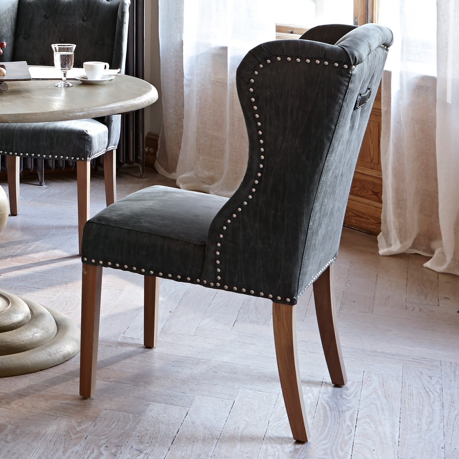 Eleganter Stuhl aus dunkelgrauem Leder mit Holzbeinen und dekorativen Nieten für Esszimmer