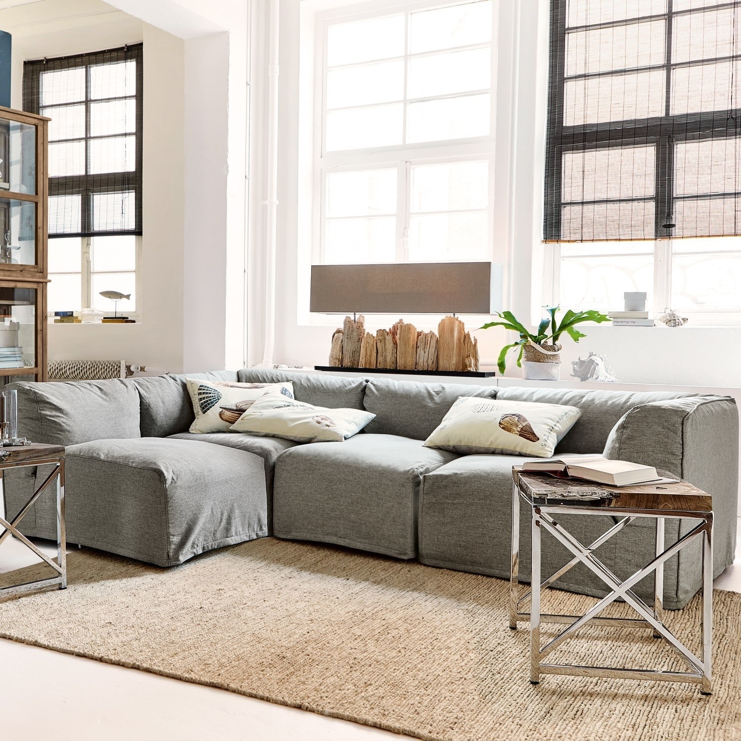 Modulares graues Sofaset aus Stoff im hellen Wohnzimmer mit Naturteppich und Beistelltisch
