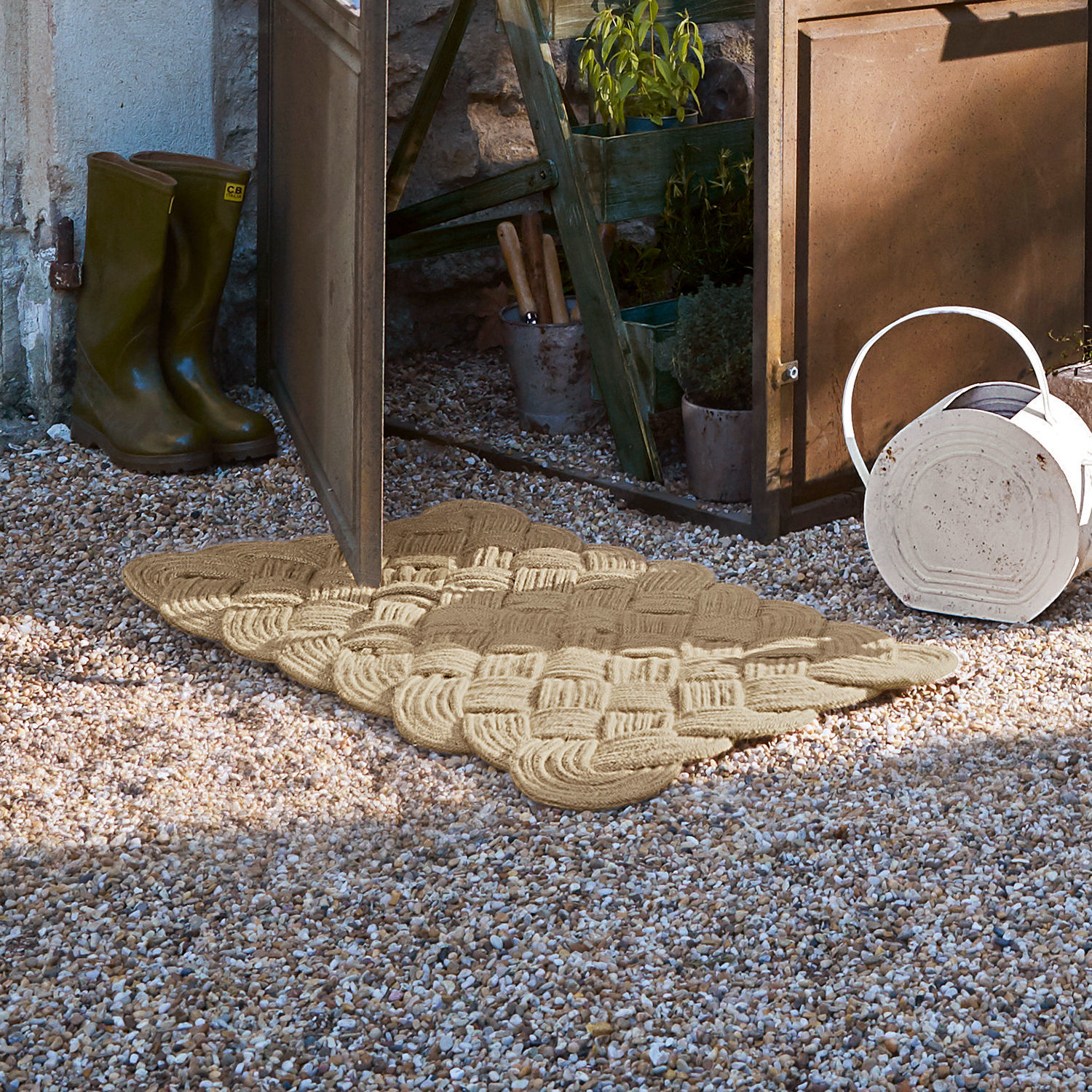 Fußmatte Harman Beige gewebte Fußmatte aus Naturmaterial auf Kiesboden vor offener Gartentür