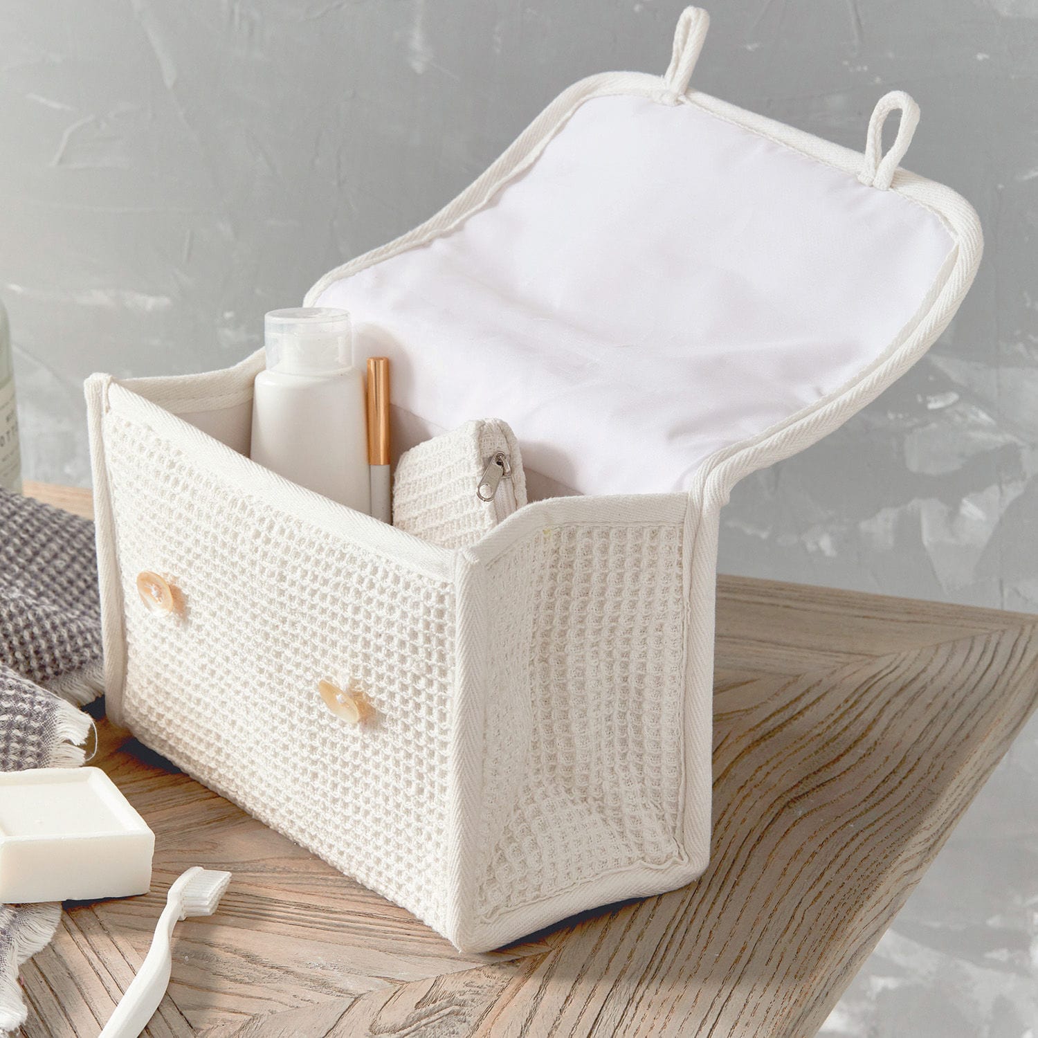 Weiße Kosmetiktasche aus Baumwolle mit Waffelstruktur und Knöpfen, ideal zur Aufbewahrung von Badutensilien