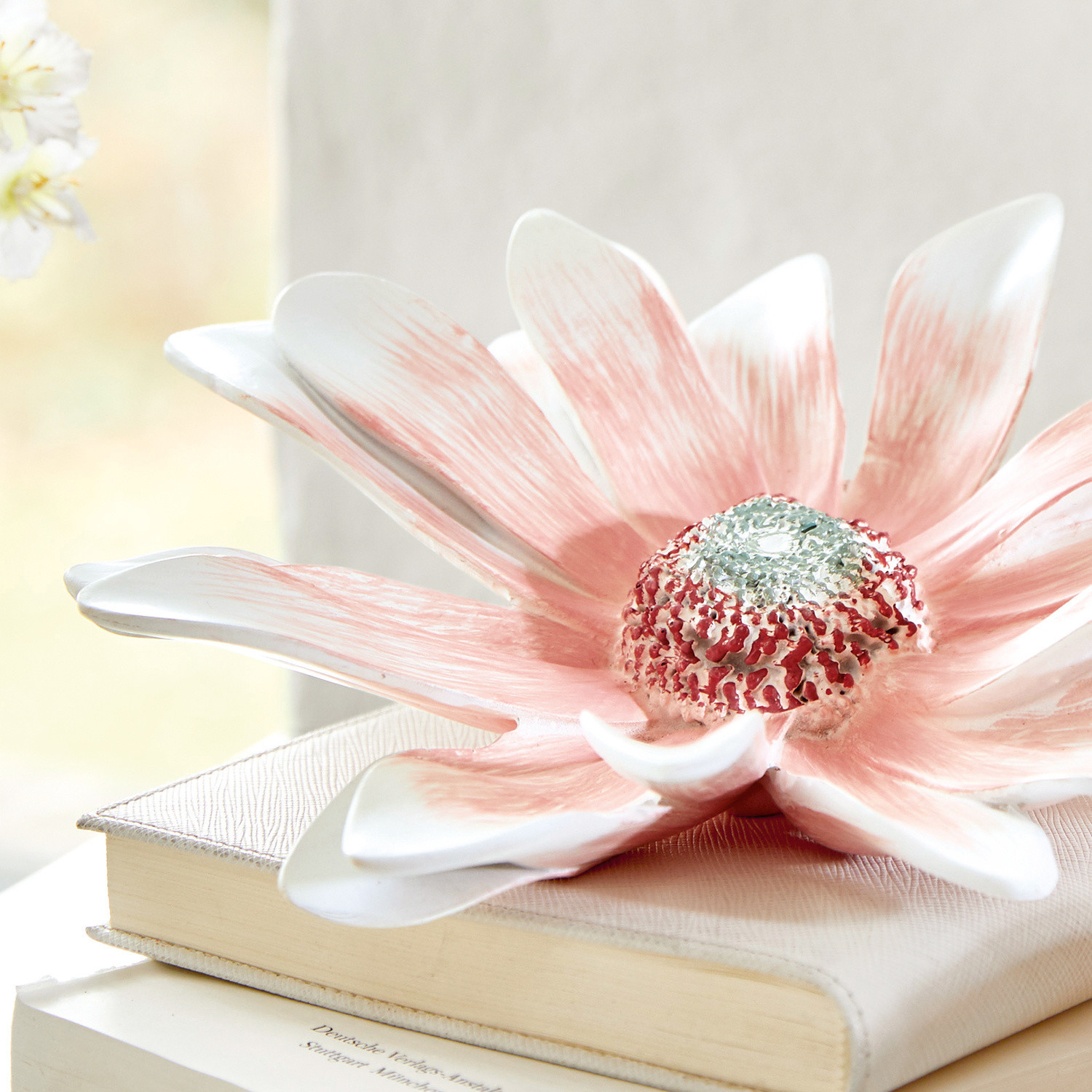 Dekorative Keramikblume in Rosa-Weiß auf Büchern, stilvolle Wohnraumdekoration