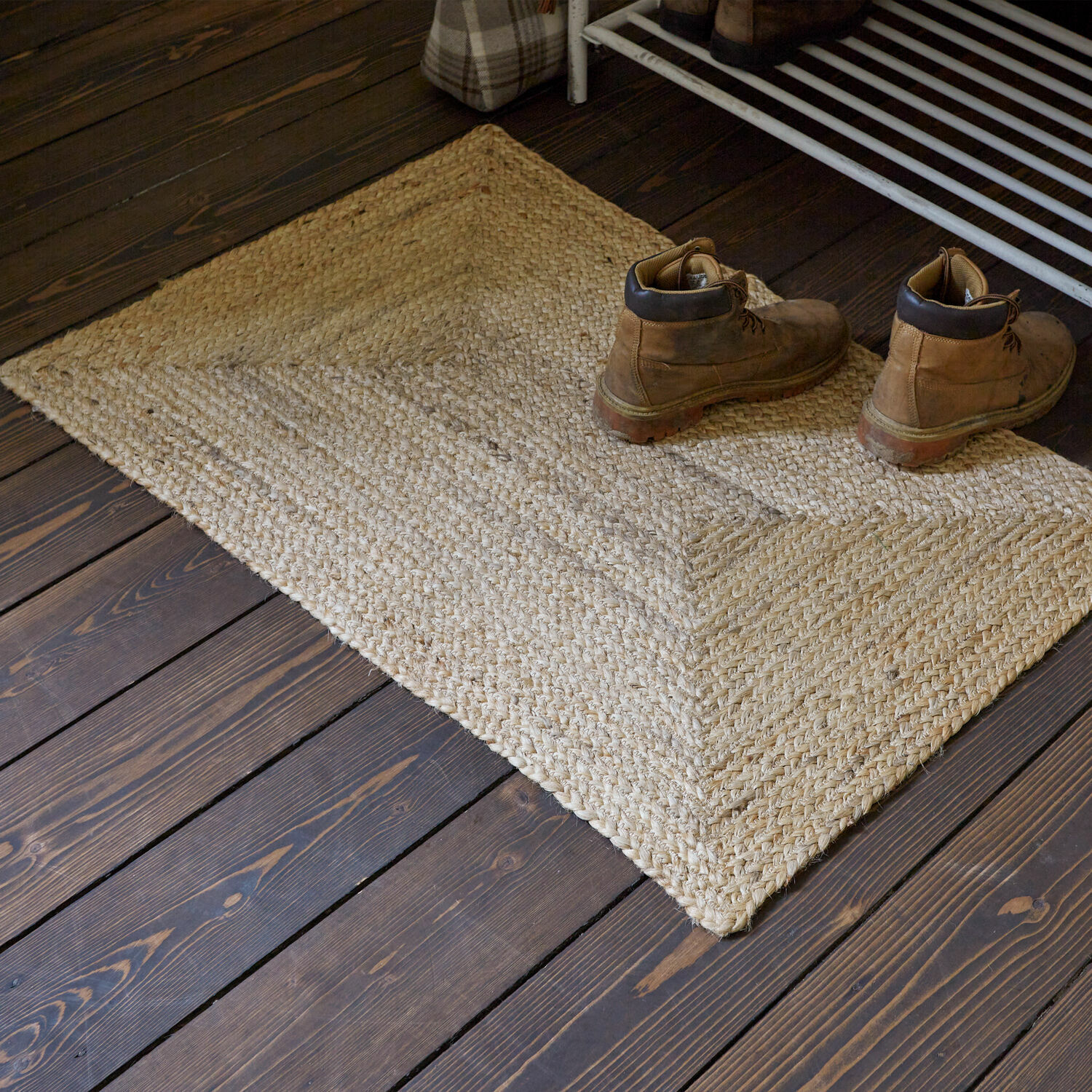 Läufer Révalaine Beiger Jute-Teppich auf dunklem Holzboden mit braunen Lederstiefeln darauf